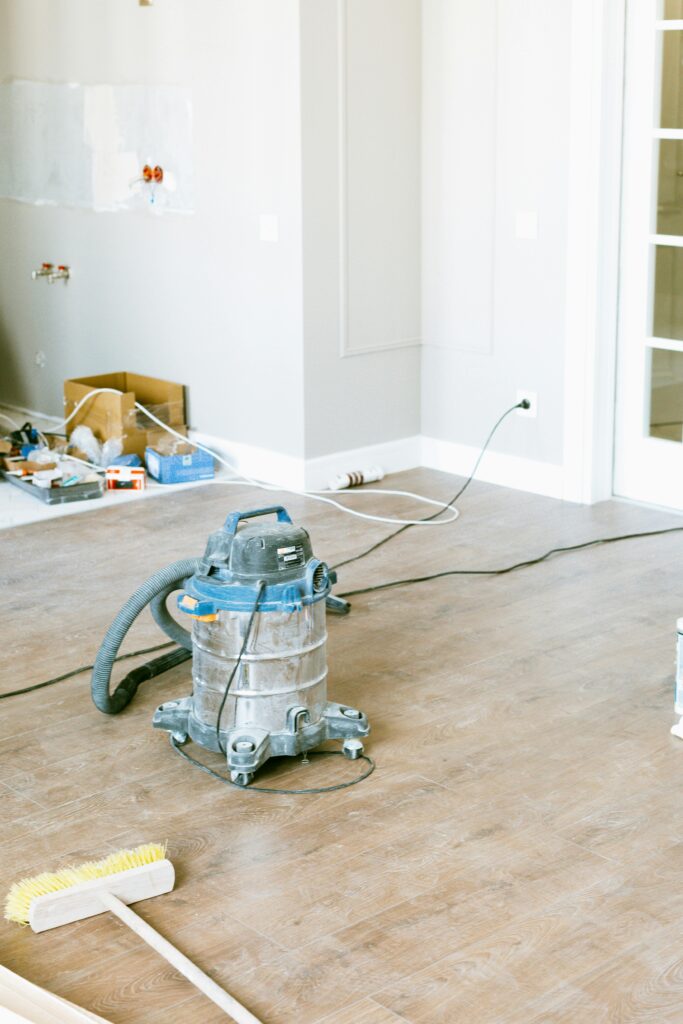 A vacuum and brush on a wood floor